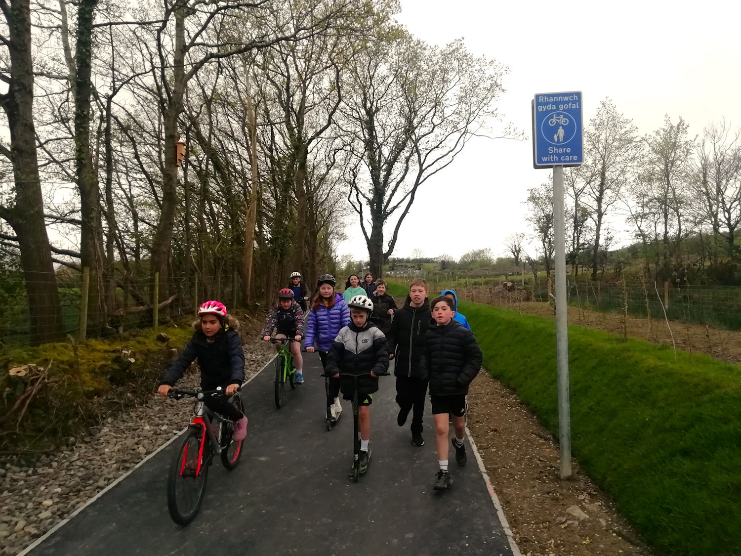 Comins Coch Primary School pupils walking, cycling and scooting on the new shared use path to Comins Coch